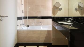 A modern bathroom with a black and white checkered floor, a glass-enclosed shower, a bathtub, and a large mirror above the sink.