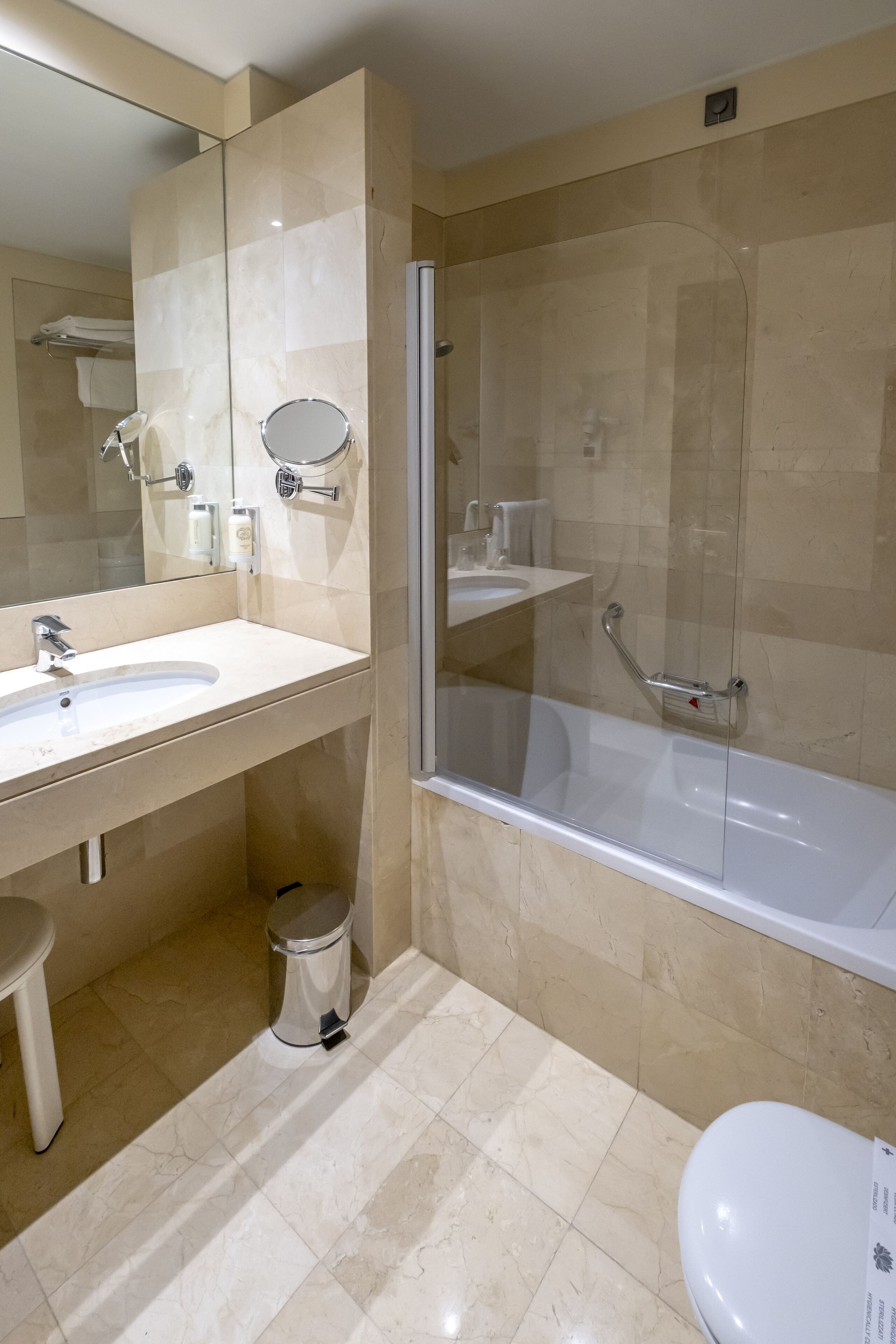 A modern bathroom with a glass-enclosed shower, a white sink, and a toilet.