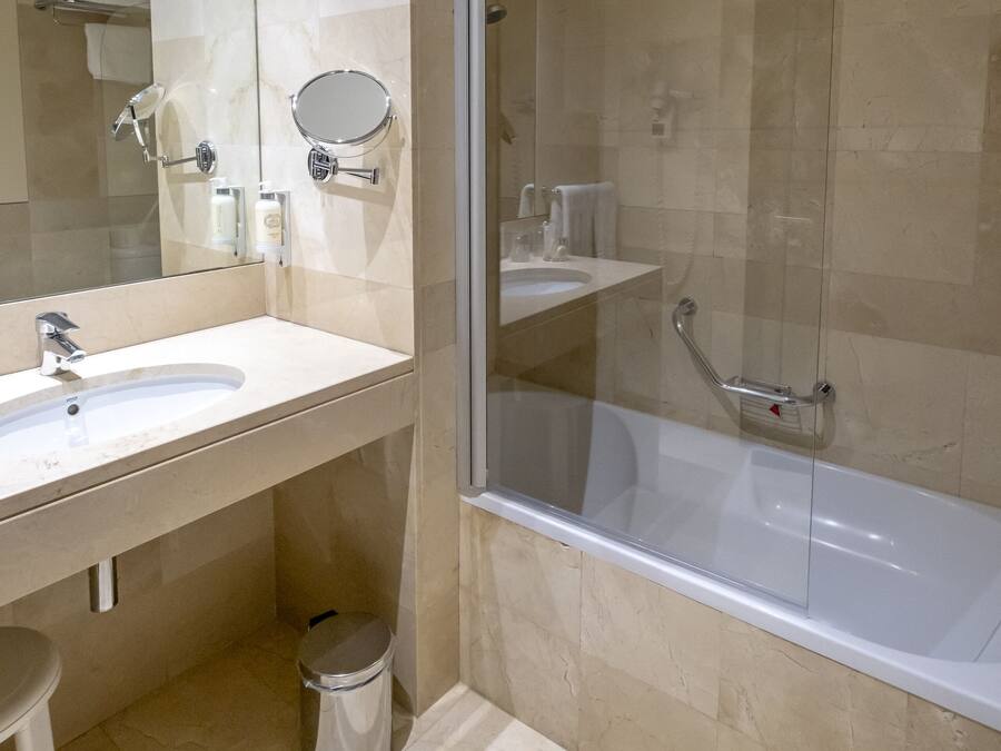 A modern bathroom with a glass-enclosed shower, a white sink, and a toilet.