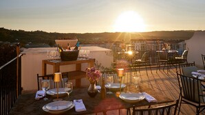 A rooftop dining area with tables set for a meal, overlooking a scenic landscape.