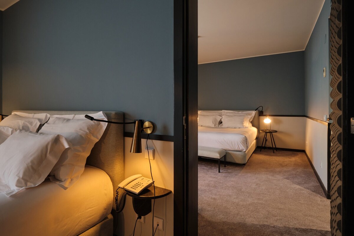 A hotel room with two beds, a bedside lamp, and a telephone.