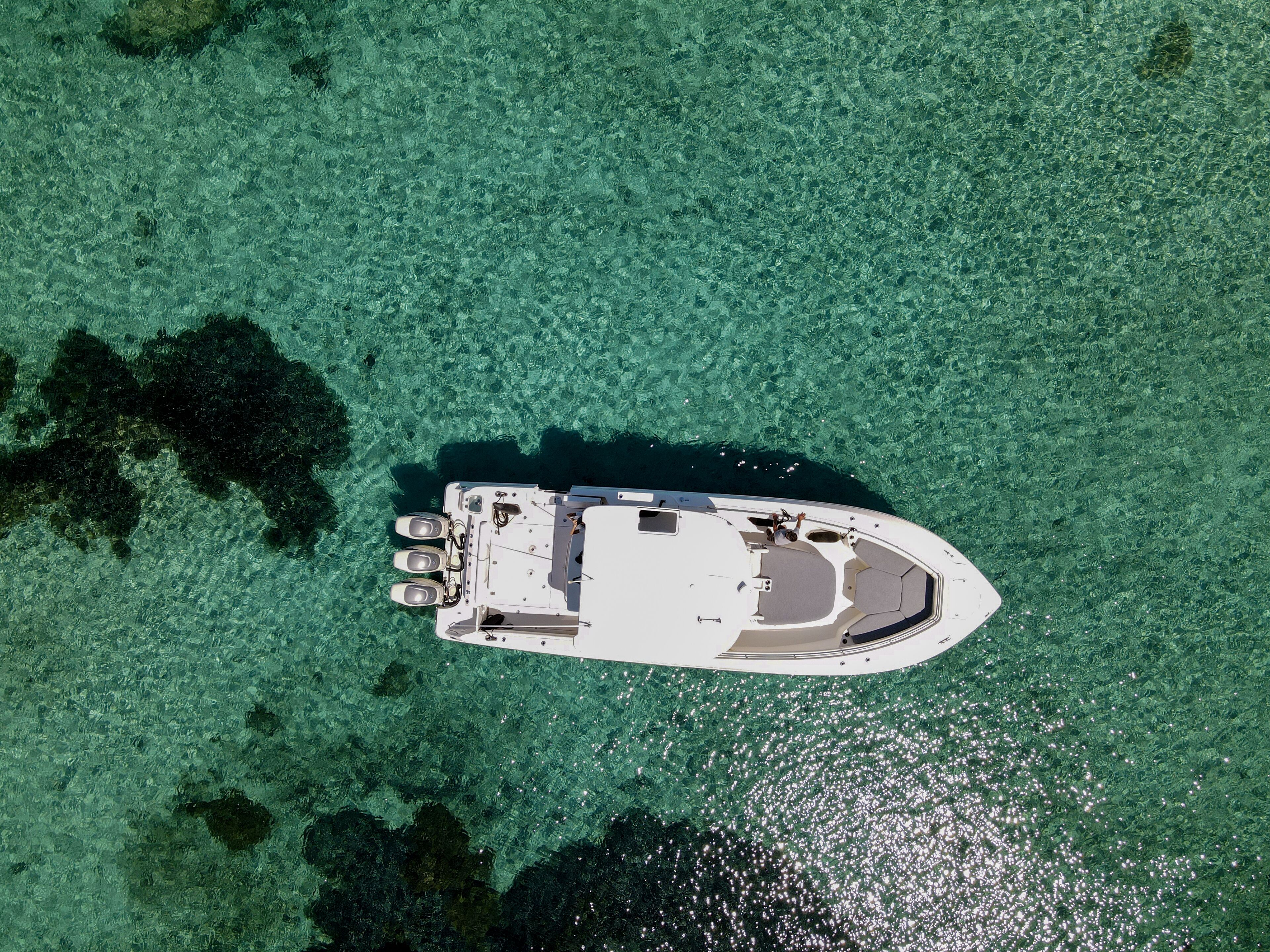 Vue aérienne d’un bateau sur une eau turquoise et limpide.