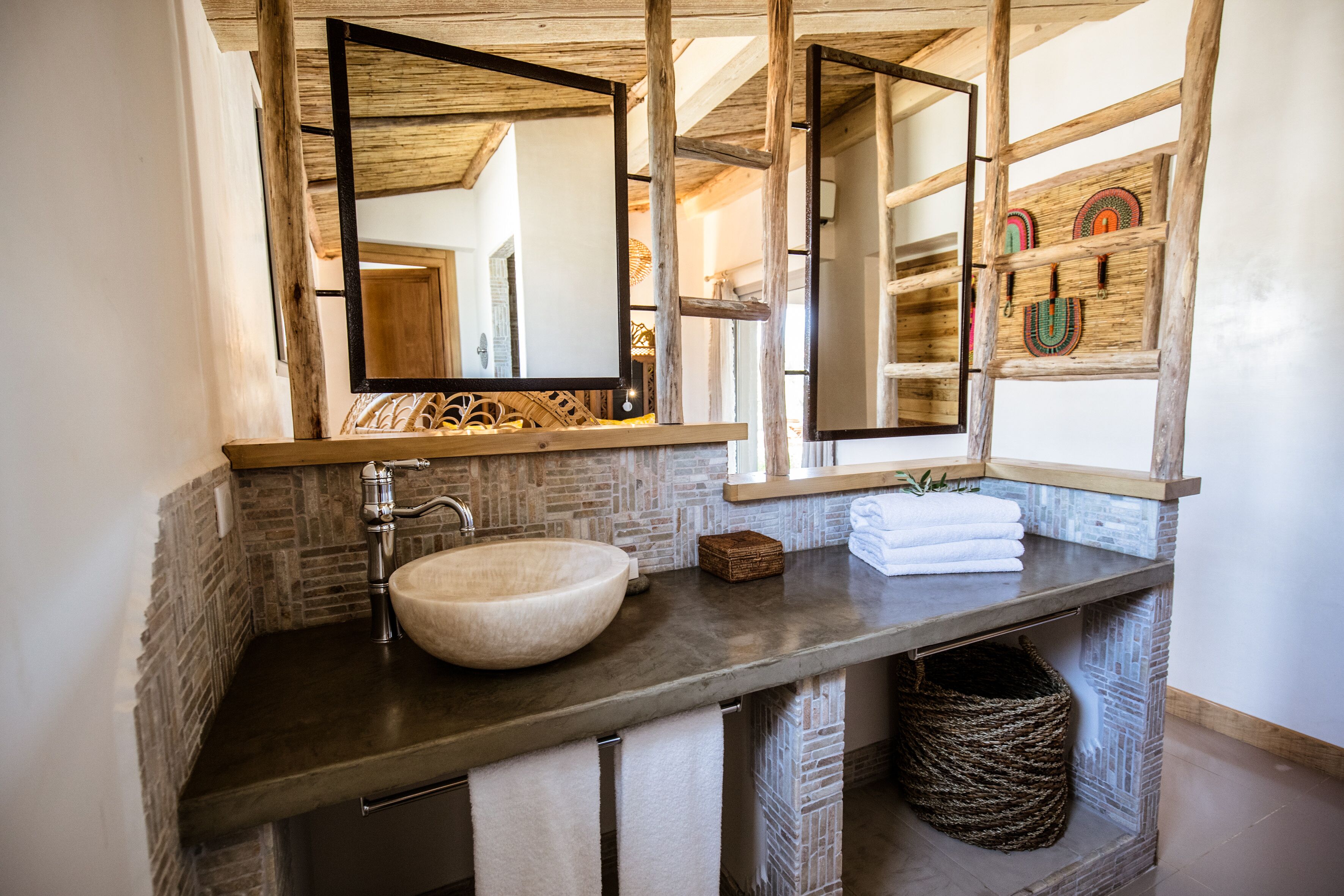 A bathroom with a large, round sink, a wooden vanity, and a mirror above the sink.