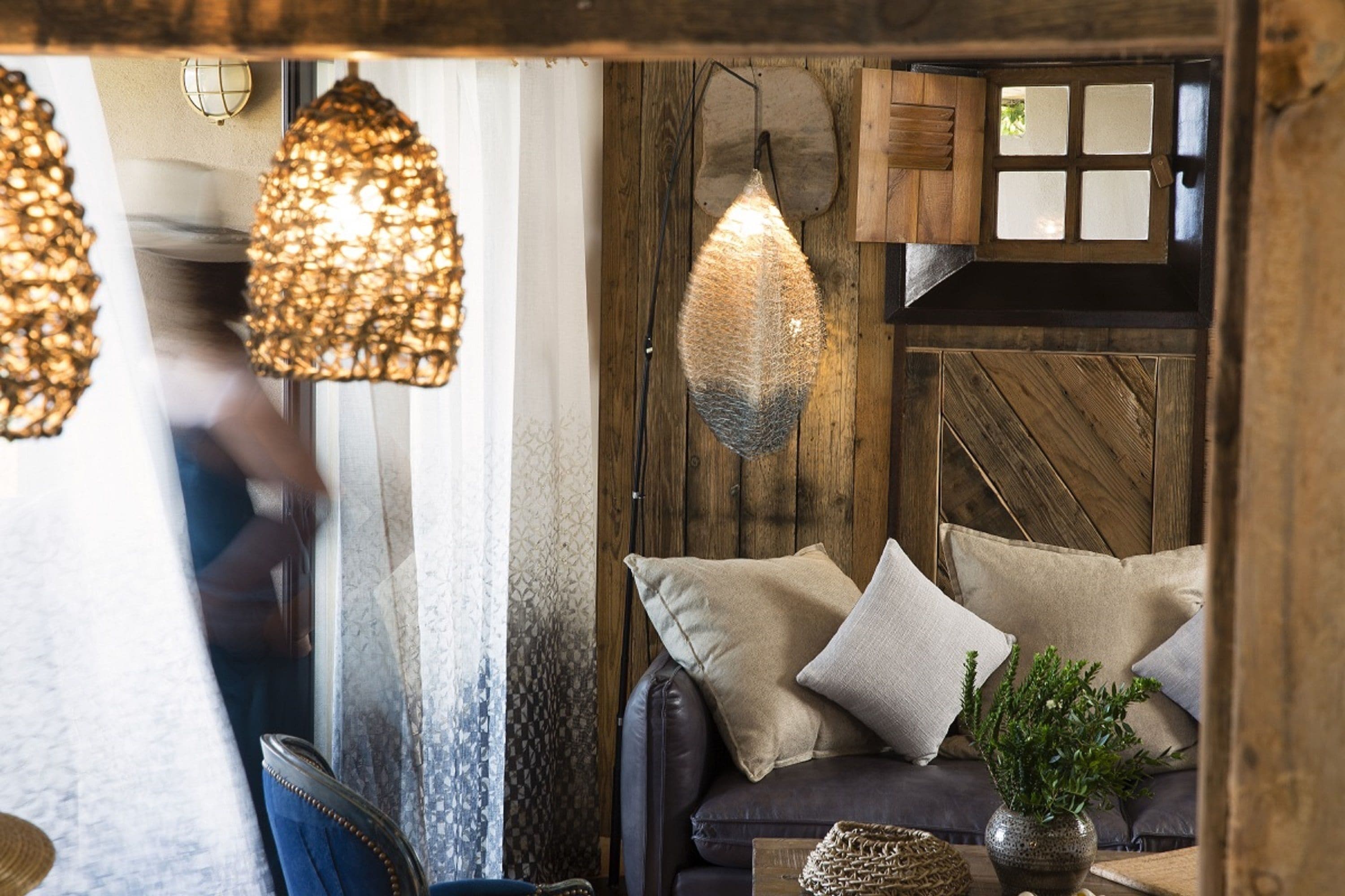 A cozy room with a wooden wall, a leather sofa, and hanging light fixtures.