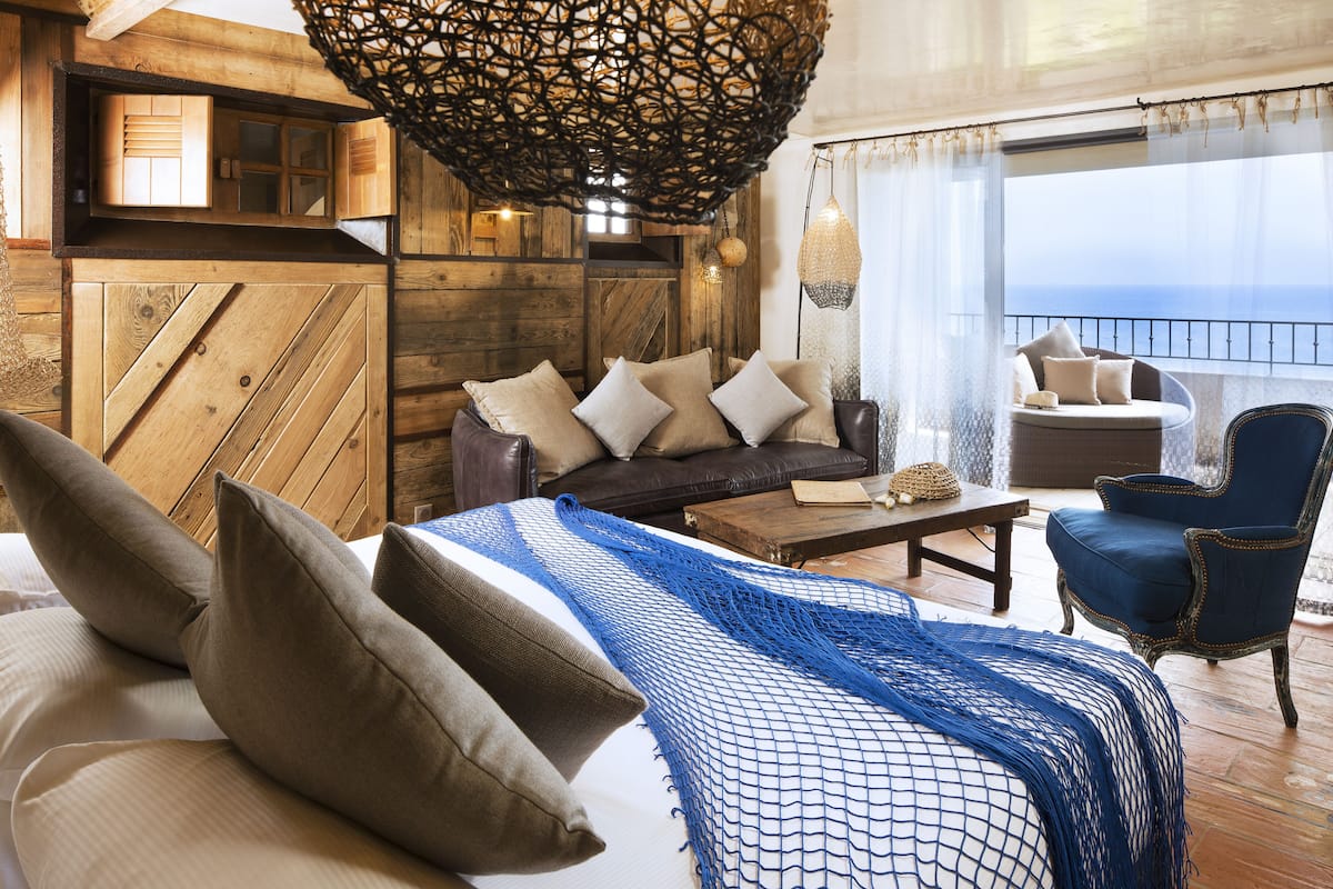 Una habitación acogedora con una cama, un sofá, una silla y vista al mar.