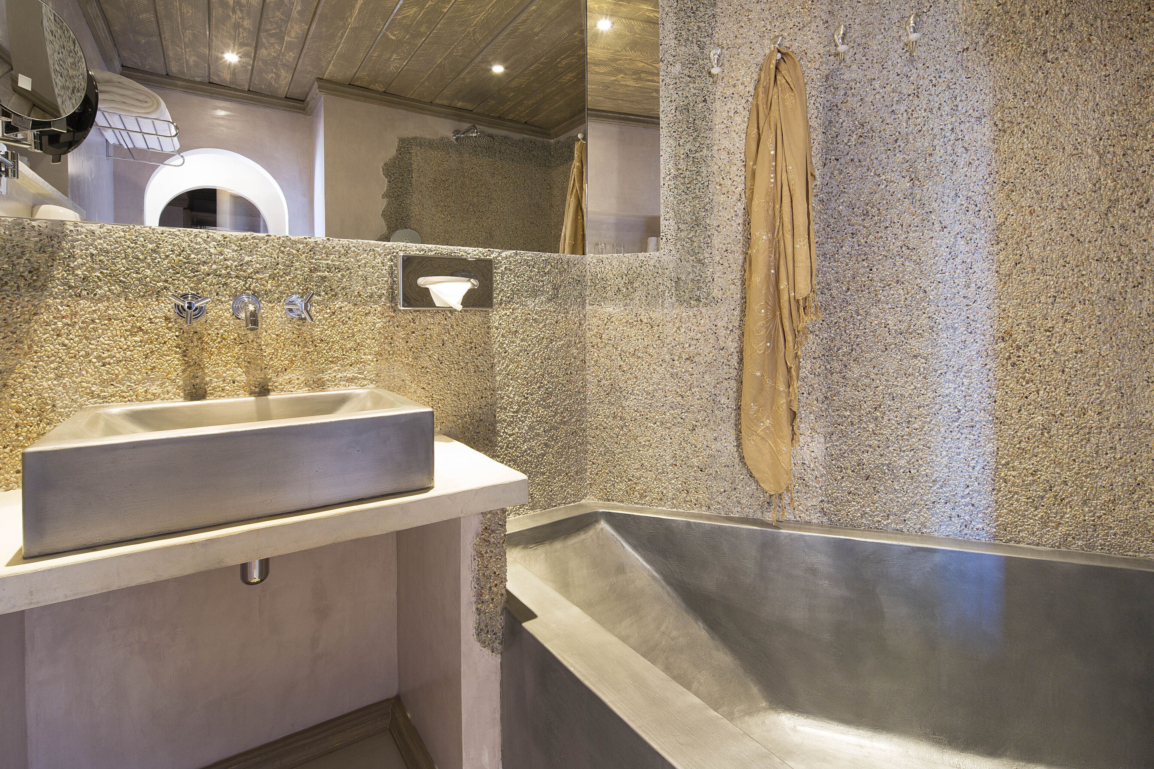 A modern bathroom with a granite countertop sink, a large bathtub, and a mirror.