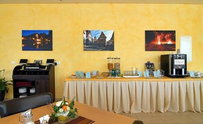 Comedor con mesa lista para una comida, una cafetera y un bufé con diferentes alimentos.