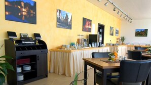 Un comedor con mesas, sillas, una estación de bufé y un florero sobre la mesa.
