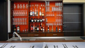 Zona de bar con estanterías llenas de botellas de licores y vasos.