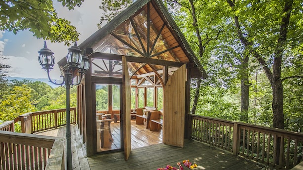 A wooden deck with a gazebo, outdoor furniture, and a view of the forest. - Nolichuckey Bluffs Cabins (Greeneville)