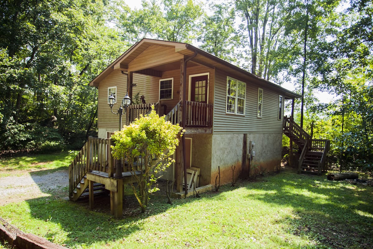 A rustic cabin with a porch, wooden steps, and a small garden.
