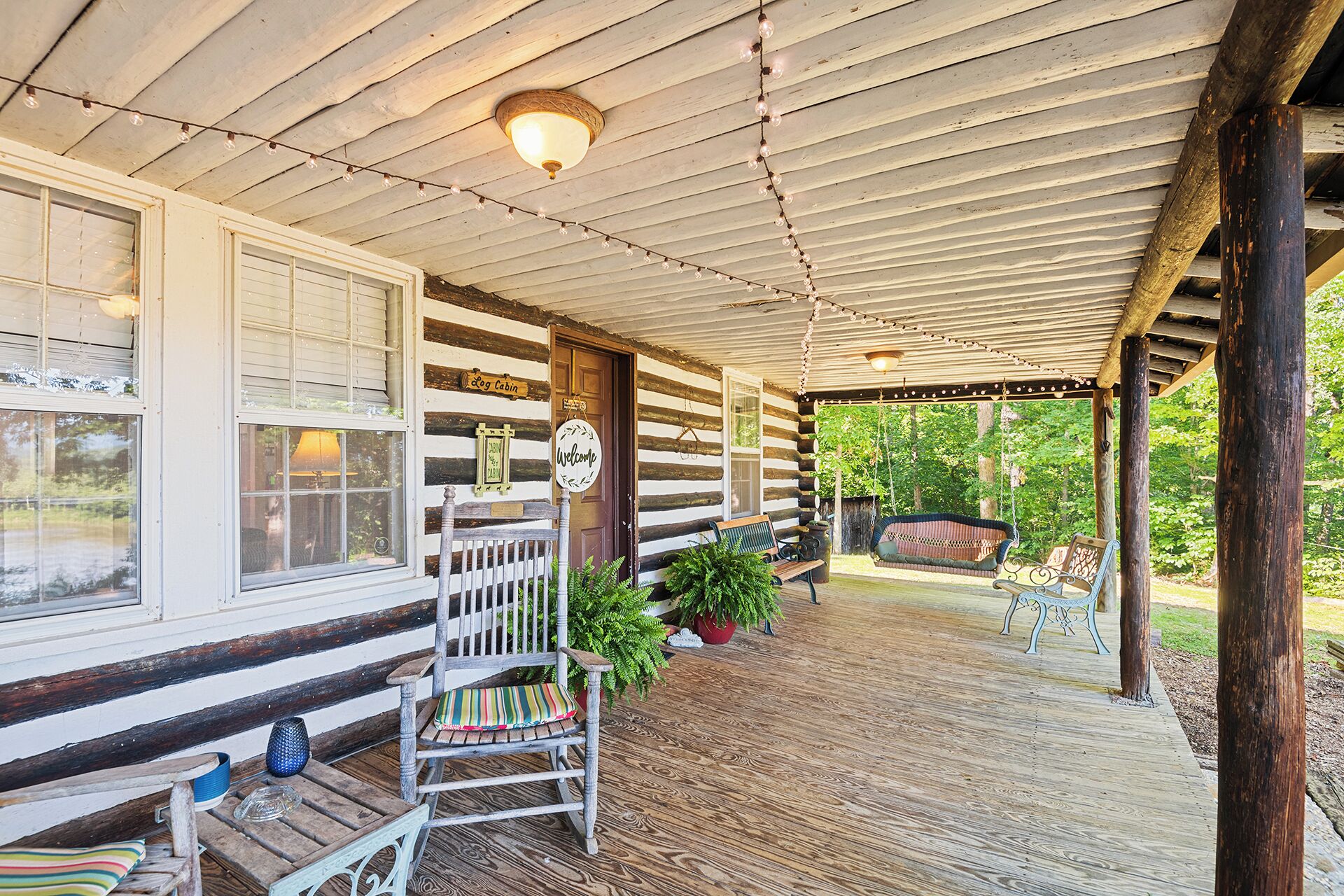 A log cabin with a porch, wooden benches, and a swing.