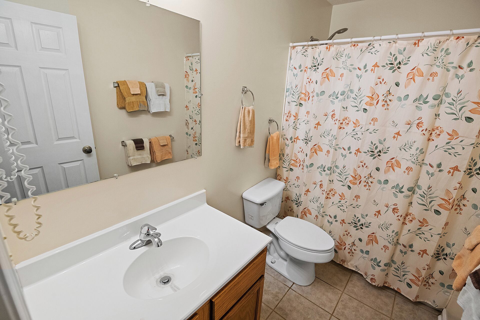 Ein Badezimmer mit weißem Waschbecken, Toilette und Duschvorhang mit Blumenmuster.