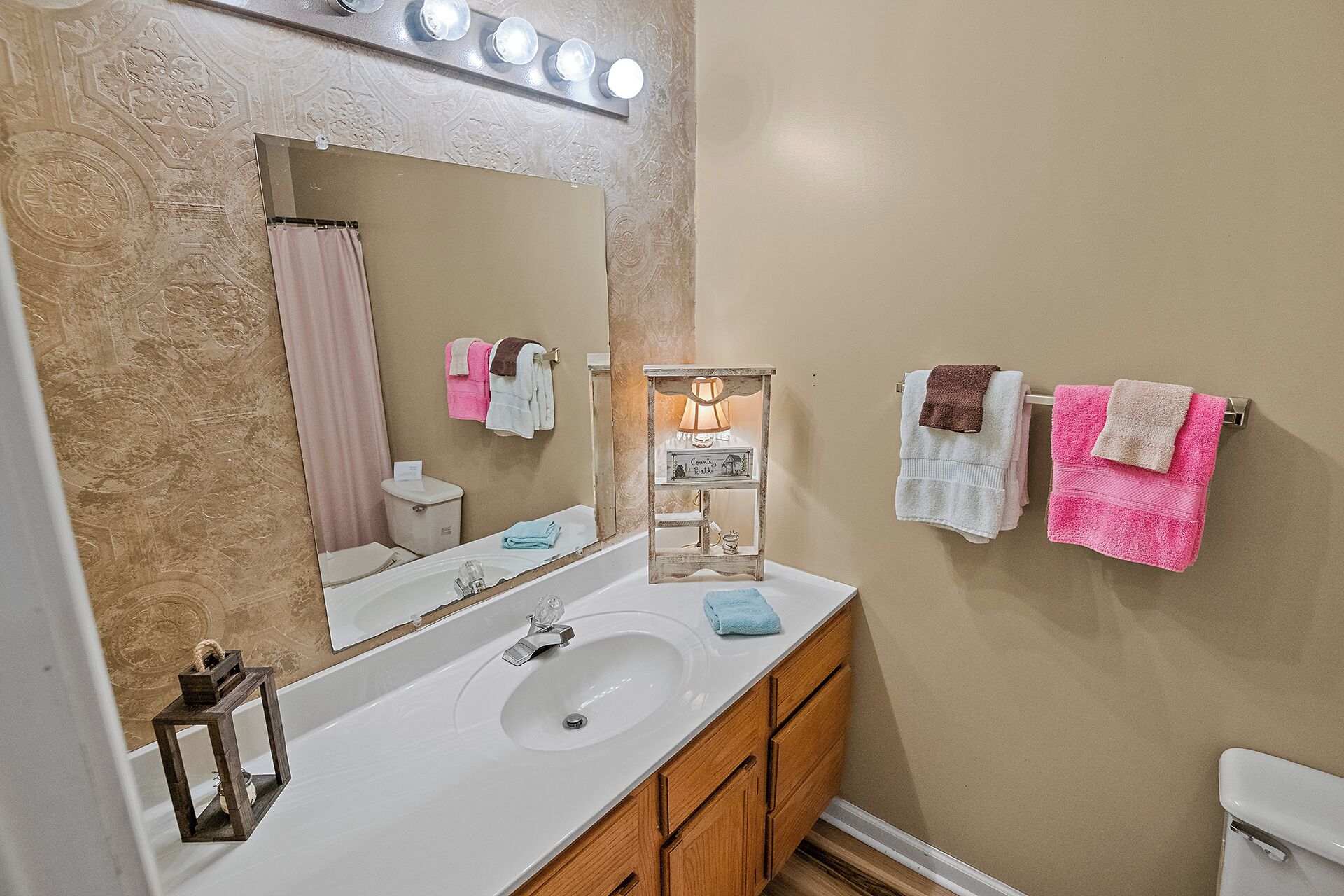 A bathroom with a white sink, wooden cabinets, a mirror, and a towel rack with multiple towels.