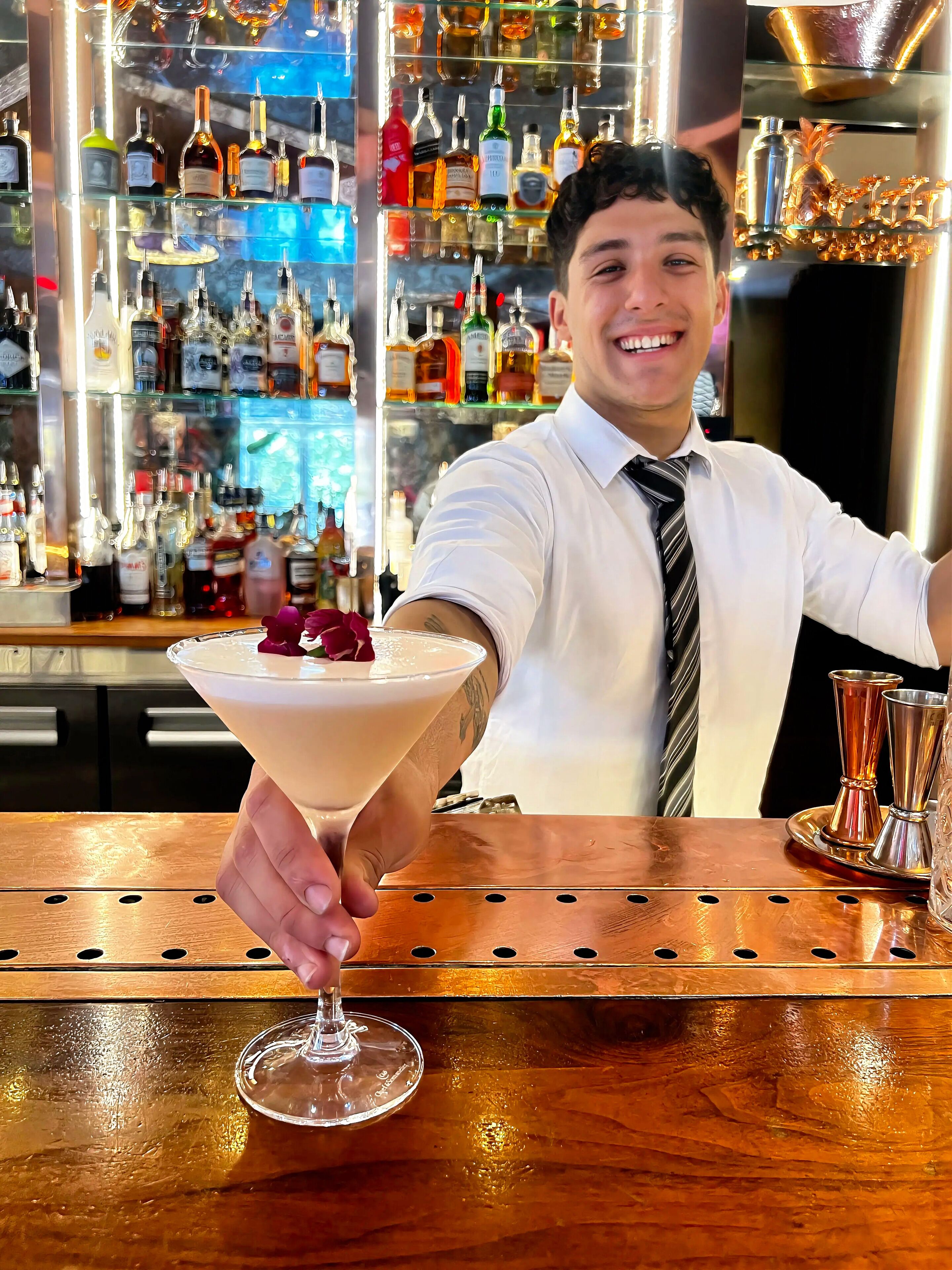 Un barman sostiene una copa de martini adornada con una rosa.