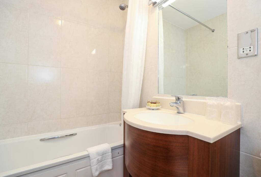 Un baño con bañera, lavamanos y espejo.