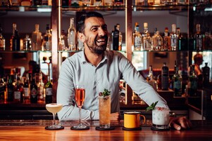 A bar with various drinks and a bartender.