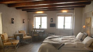 A bedroom with a bed, two chairs, a desk, and two windows. - Hotel Sven Vintappare (Stockholm)