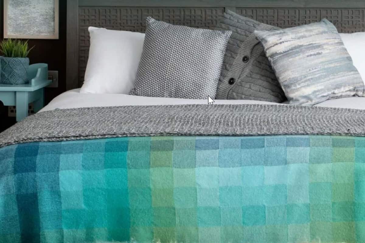 A neatly made bed with a checkered blanket, pillows, and a headboard.