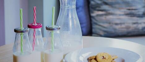 A table with three milk bottles, a large water bottle, and a plate with cookies.