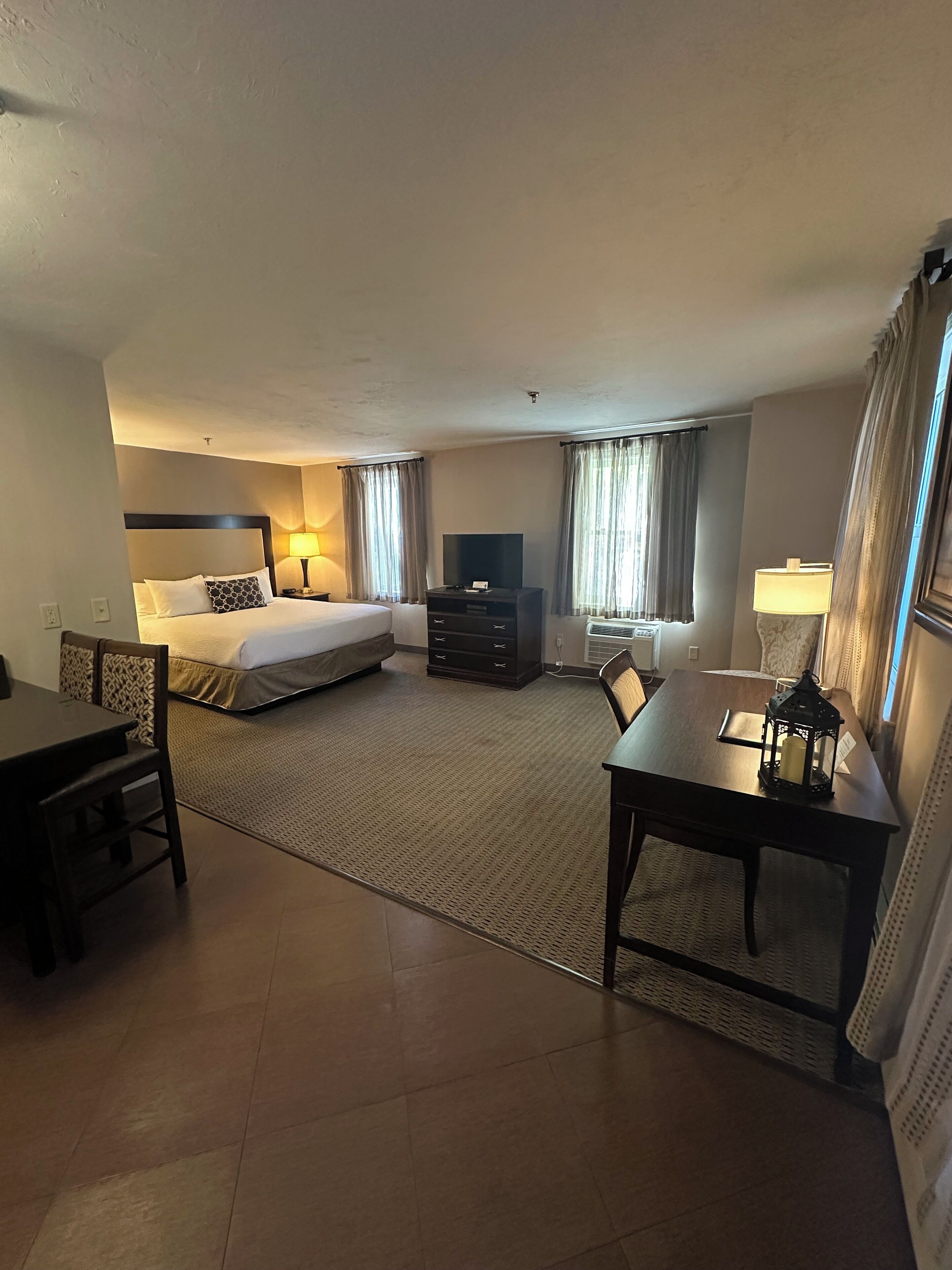 A hotel room with a bed, a desk, a TV, and a lamp.