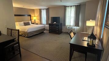 A hotel room with a bed, a desk, a TV, and a lamp.