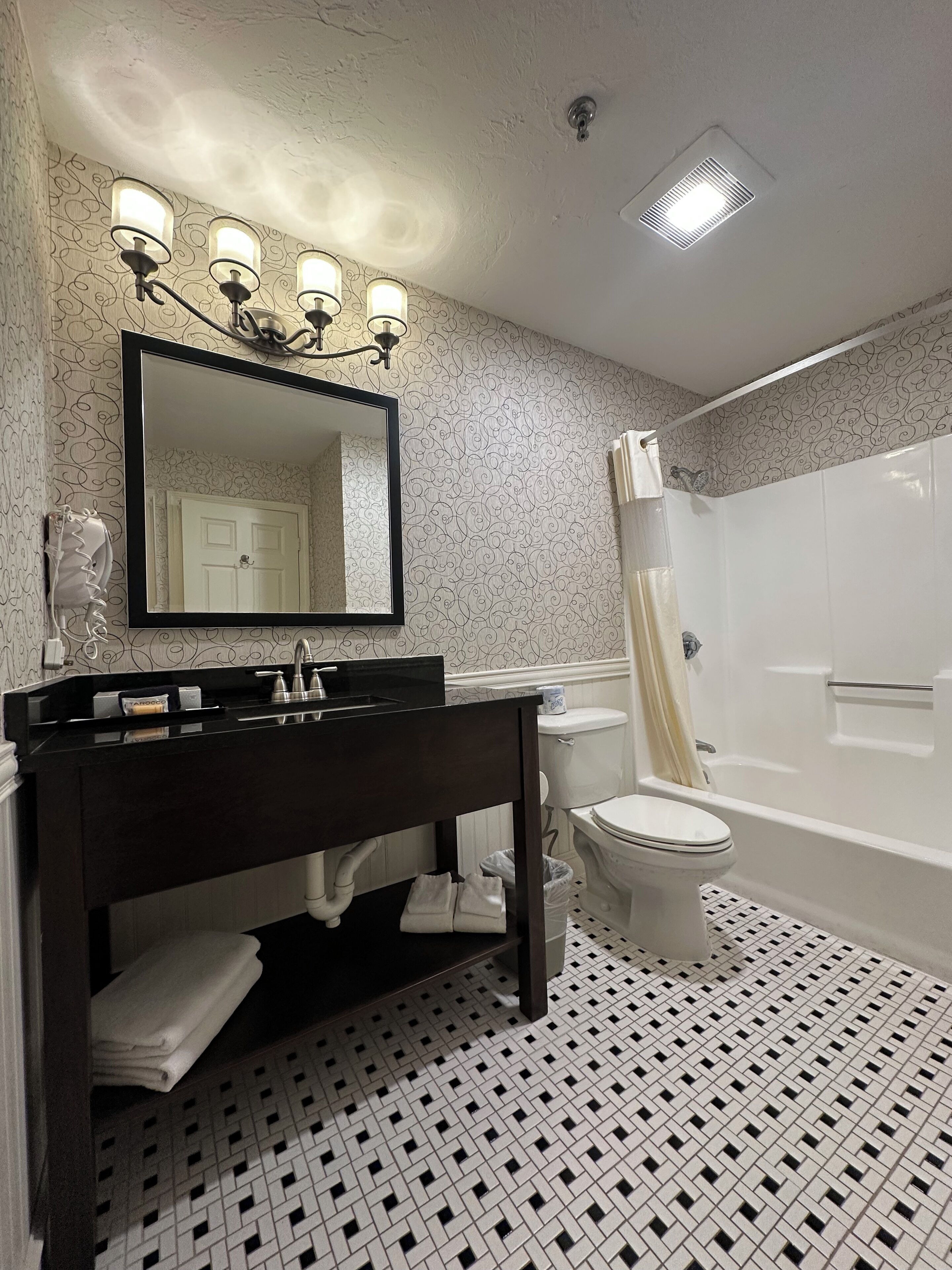 Un baño con tocador negro, inodoro blanco, bañera y ducha.