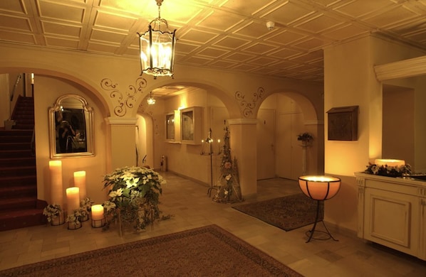 Um amplo salão com escadaria, lustres e iluminação decorativa.