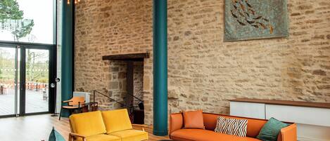 Un salon moderne avec un mur en pierre, une cheminée et une grande fenêtre donnant sur une terrasse.