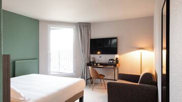 Una habitación de hotel con una cama, un escritorio, una silla, un televisor y una lámpara.