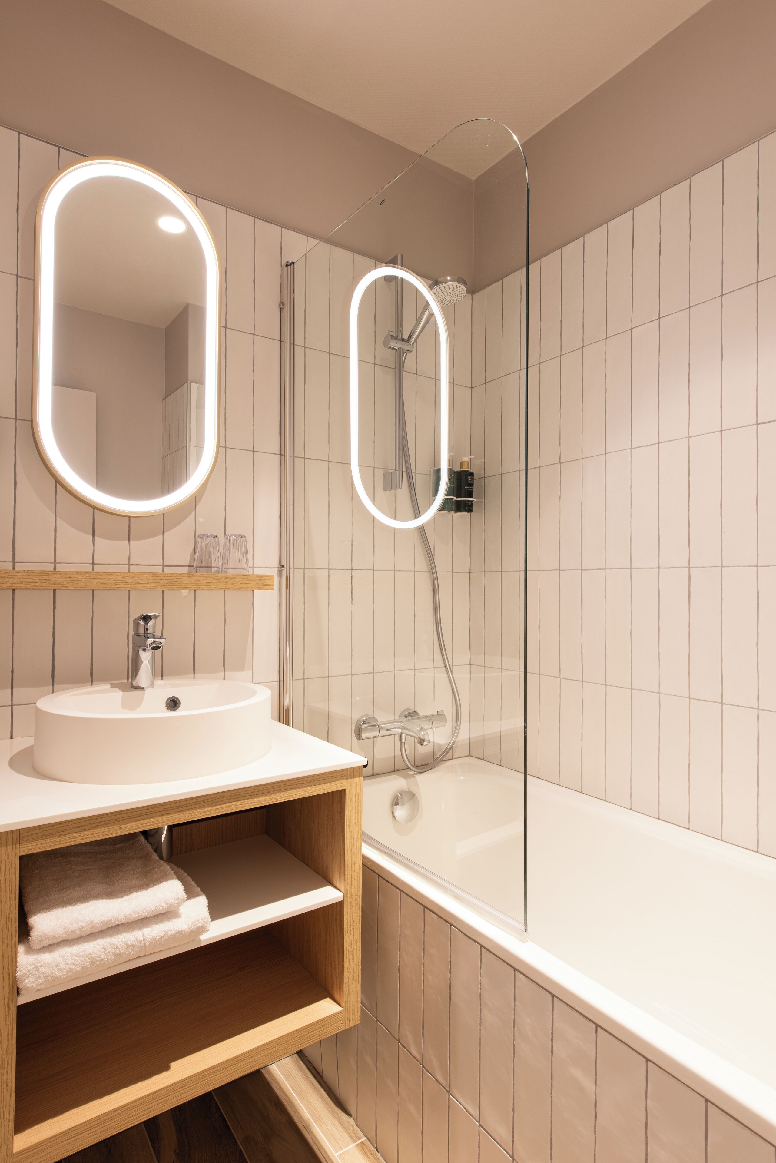 Ein modernes Badezimmer mit einem weißen Waschbecken, Spiegel und Dusche.