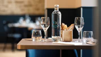 Une table avec une bouteille, des verres et un panier de pain.