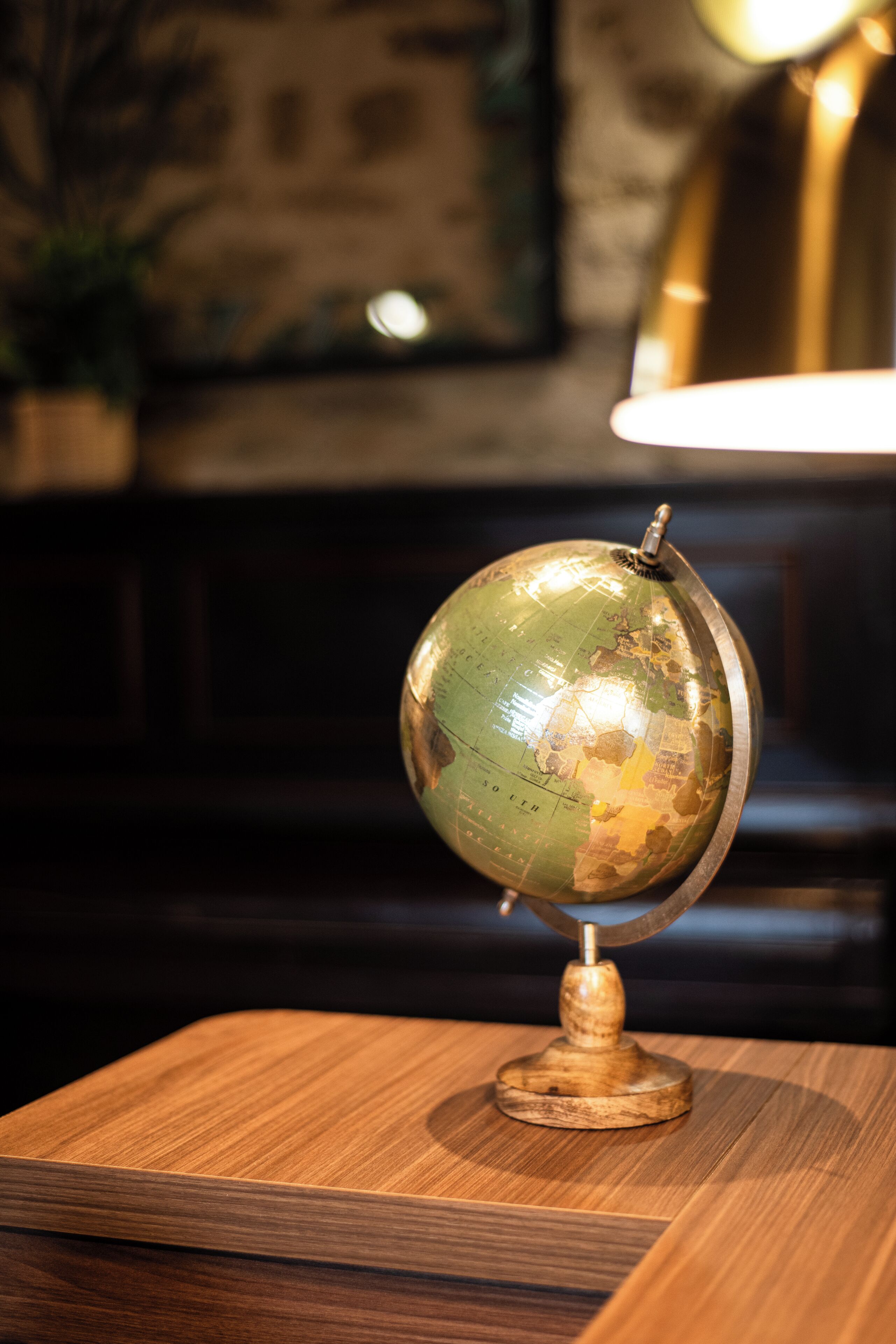 Un globe terrestre posé sur une table en bois, avec une lampe en arrière-plan.