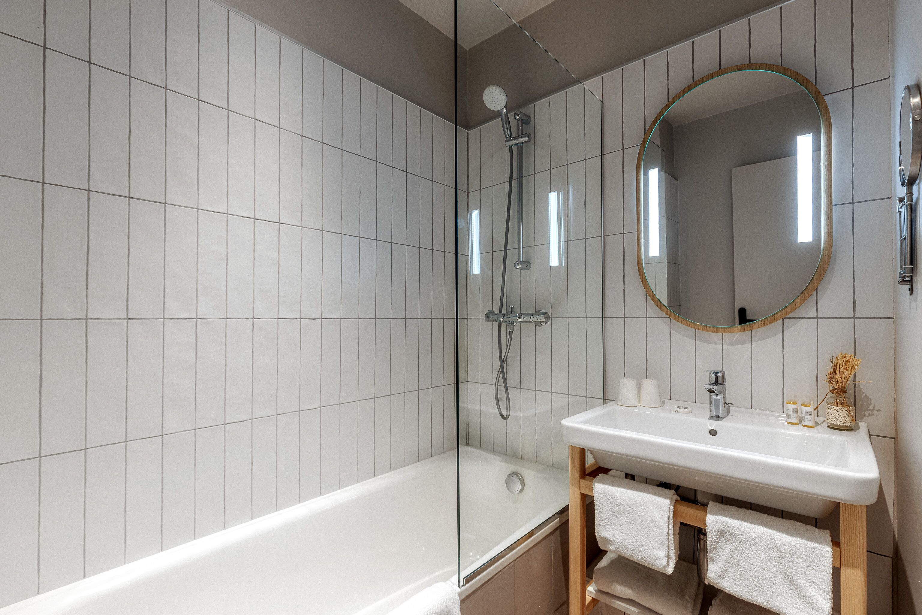 Un baño moderno con ducha acristalada, lavabo blanco y tocador de madera.