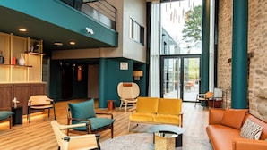 Un vestíbulo amplio con techo alto, muebles modernos y un gran ventanal con vistas al exterior.