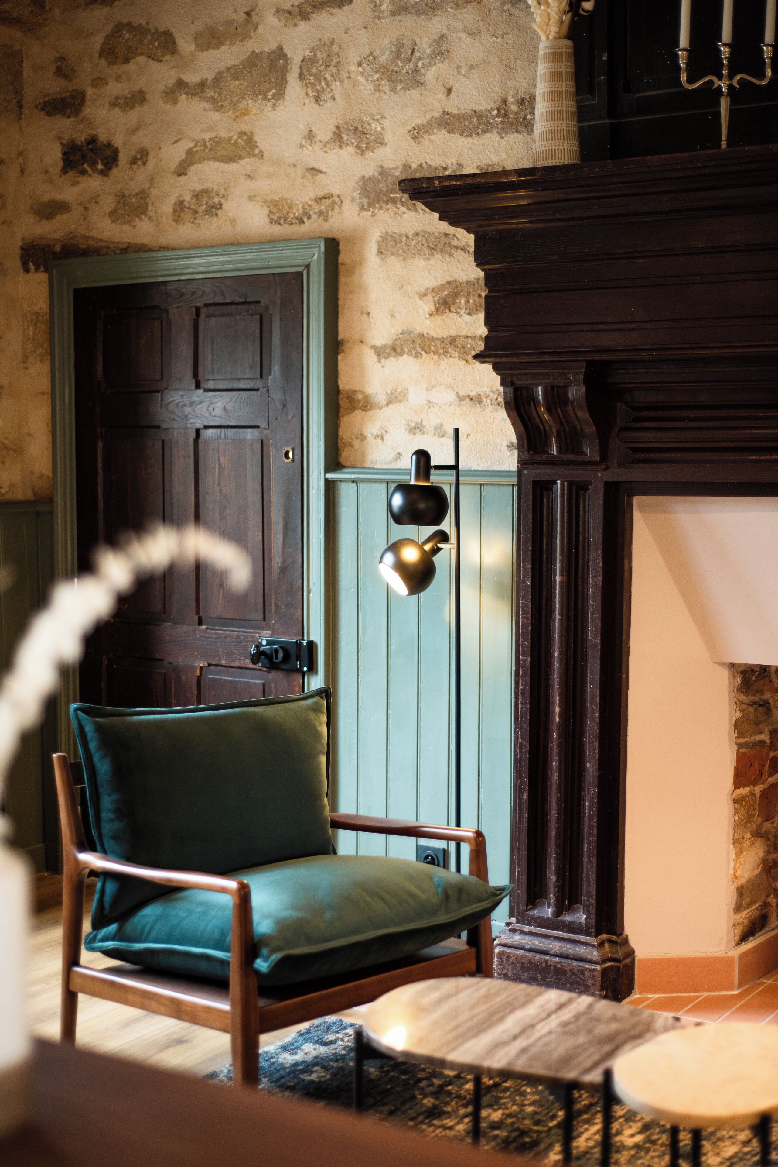 A room with a wooden chair, a small round table, a door, and a wall-mounted light fixture.
