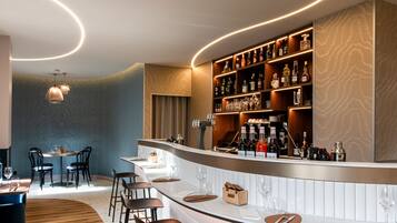 A modern bar area with a curved counter, bar stools, and a wine rack.