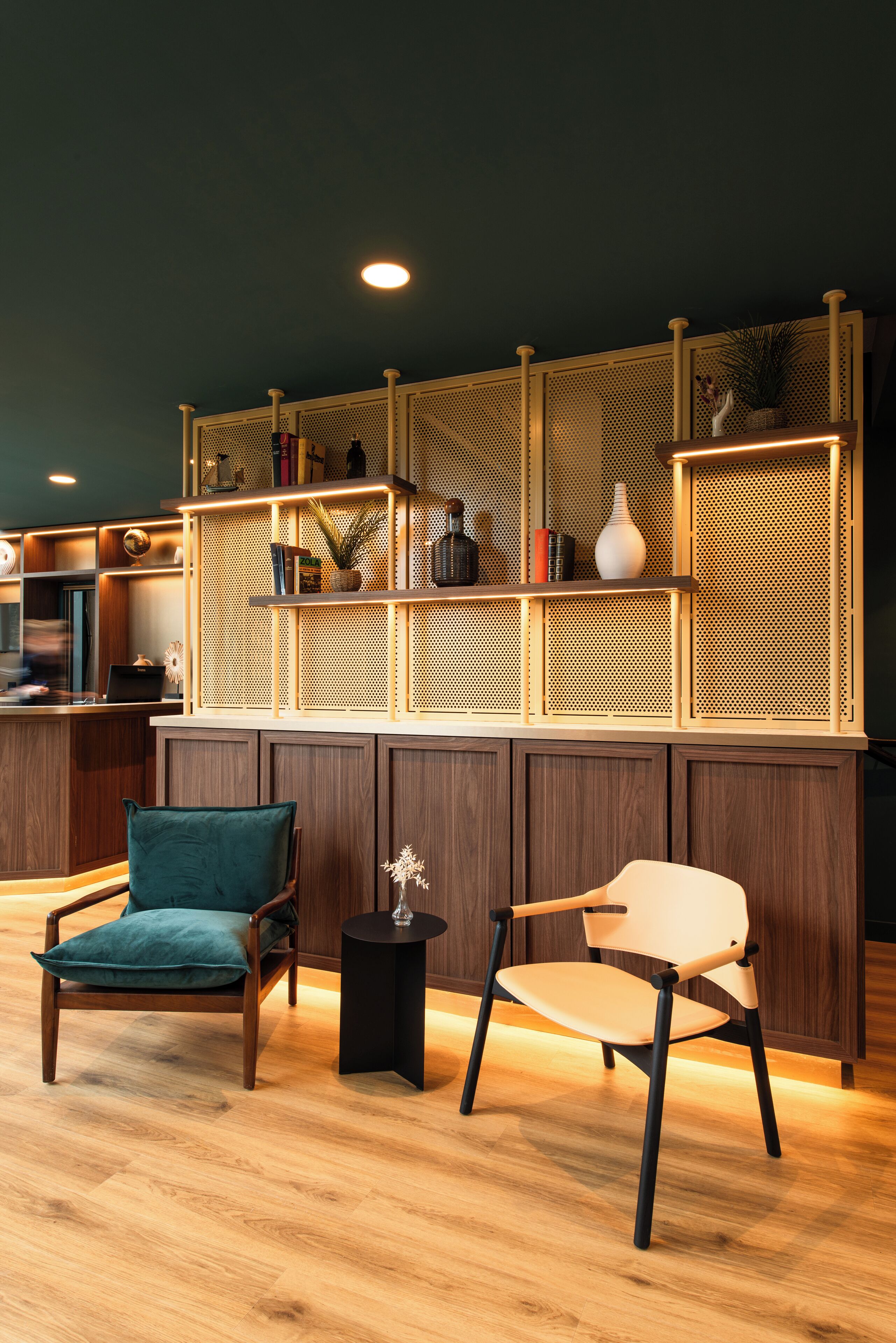 A modern interior with two chairs, a small table, and a decorative shelf with various items.