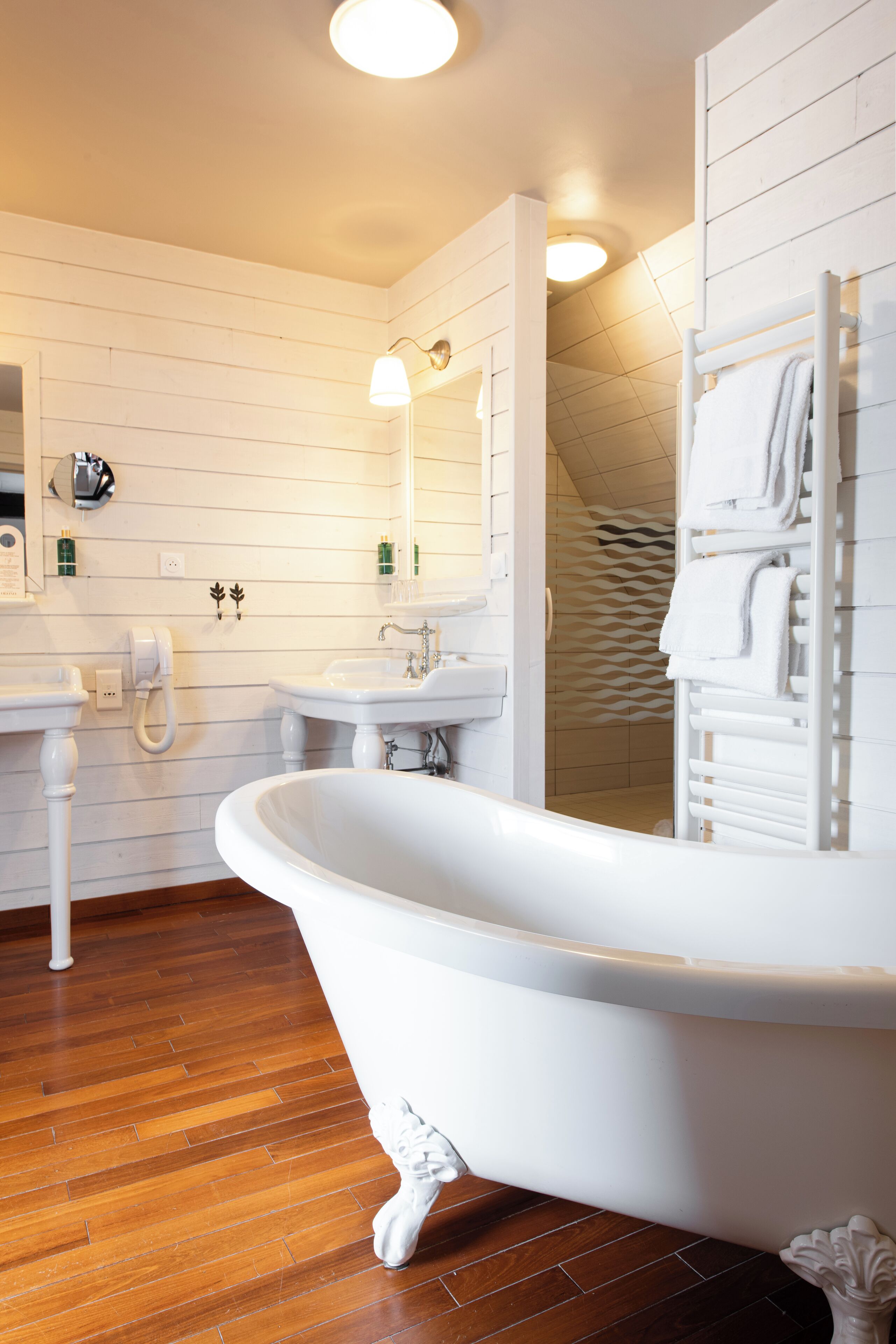 A bathroom with a freestanding bathtub, two sinks, and a mirror.