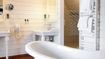 A bathroom with a freestanding bathtub, two sinks, and a mirror.