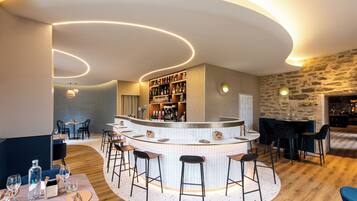 Zona de bar moderna con barra curva, taburetes y una variedad de botellas.