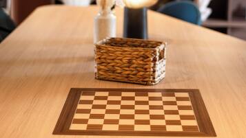 A wooden table with a chessboard, a vase with dried plants, and a spherical lamp.