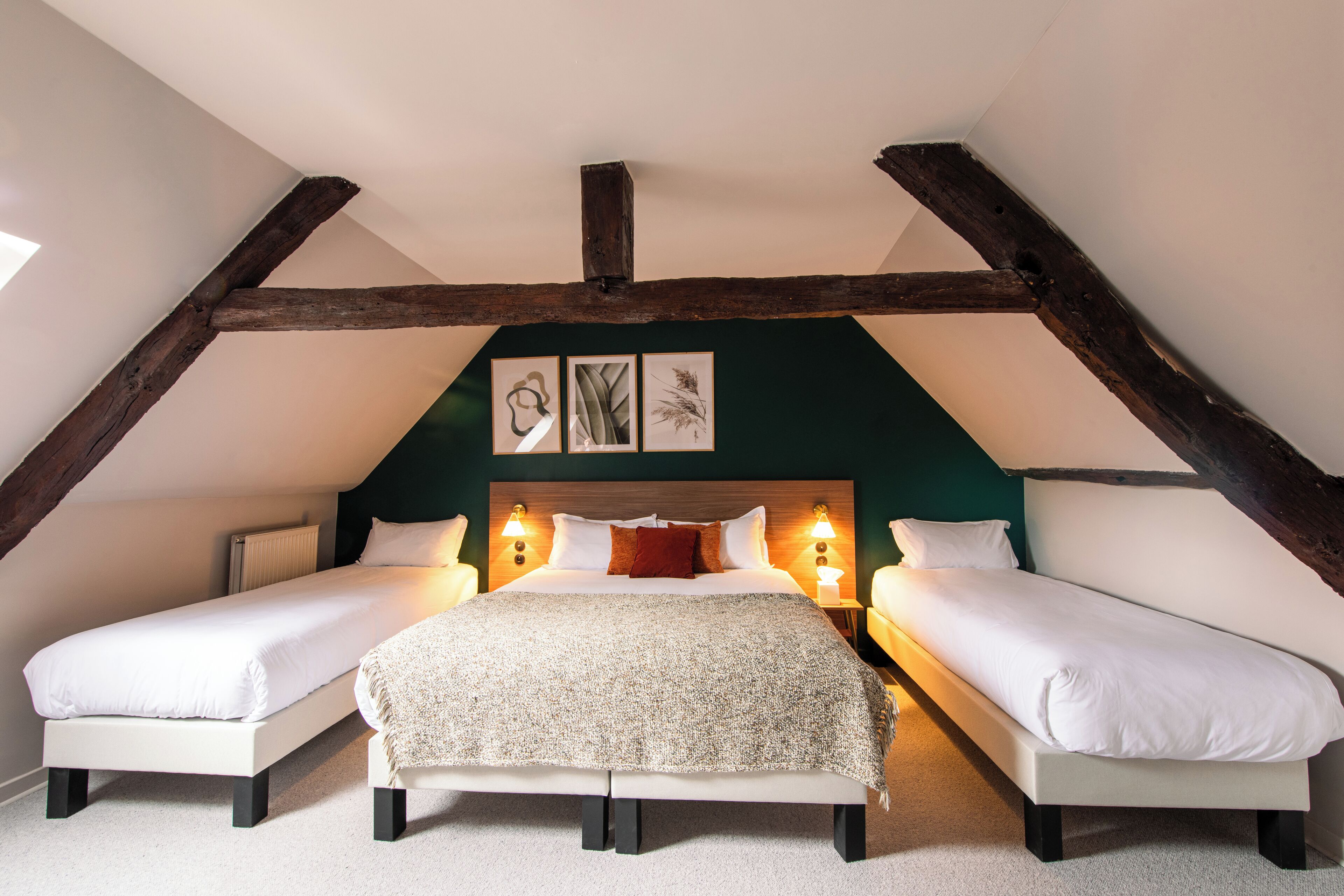 Un dormitorio con dos camas individuales, una cama grande y una estructura de techo de madera.
