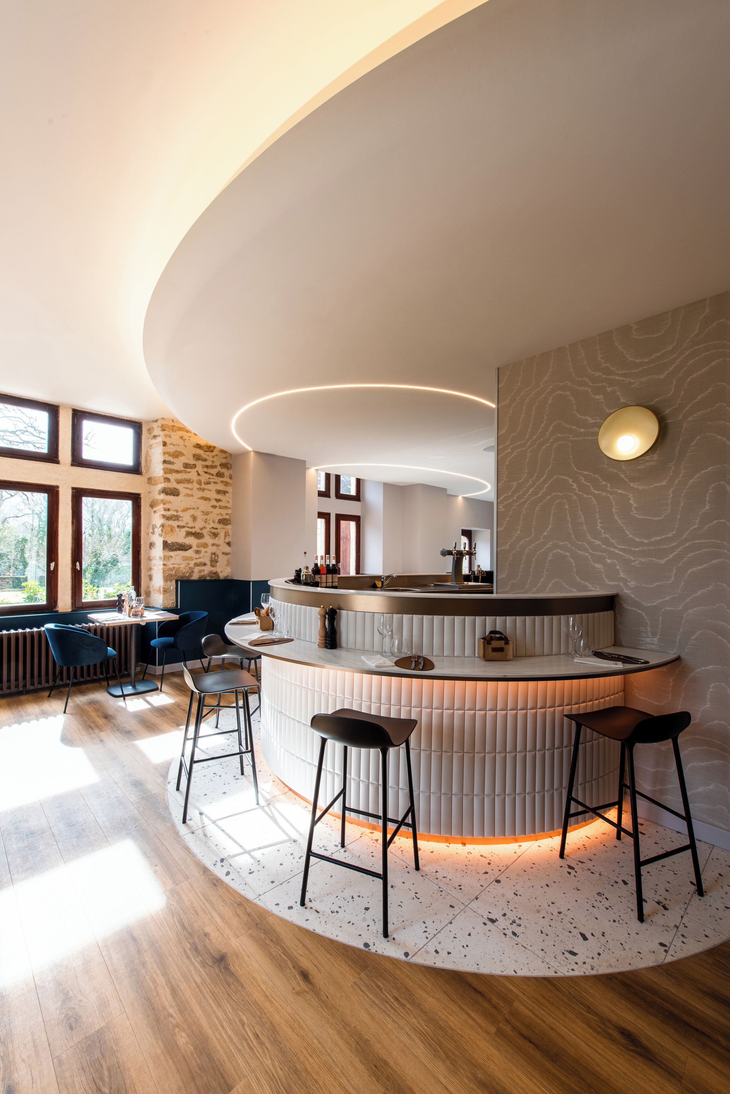 Una cocina moderna con una isla curvada, taburetes de bar y vistas al exterior.