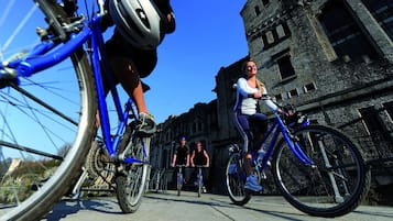 A group of cyclists on a paved path with a historic building in the background.