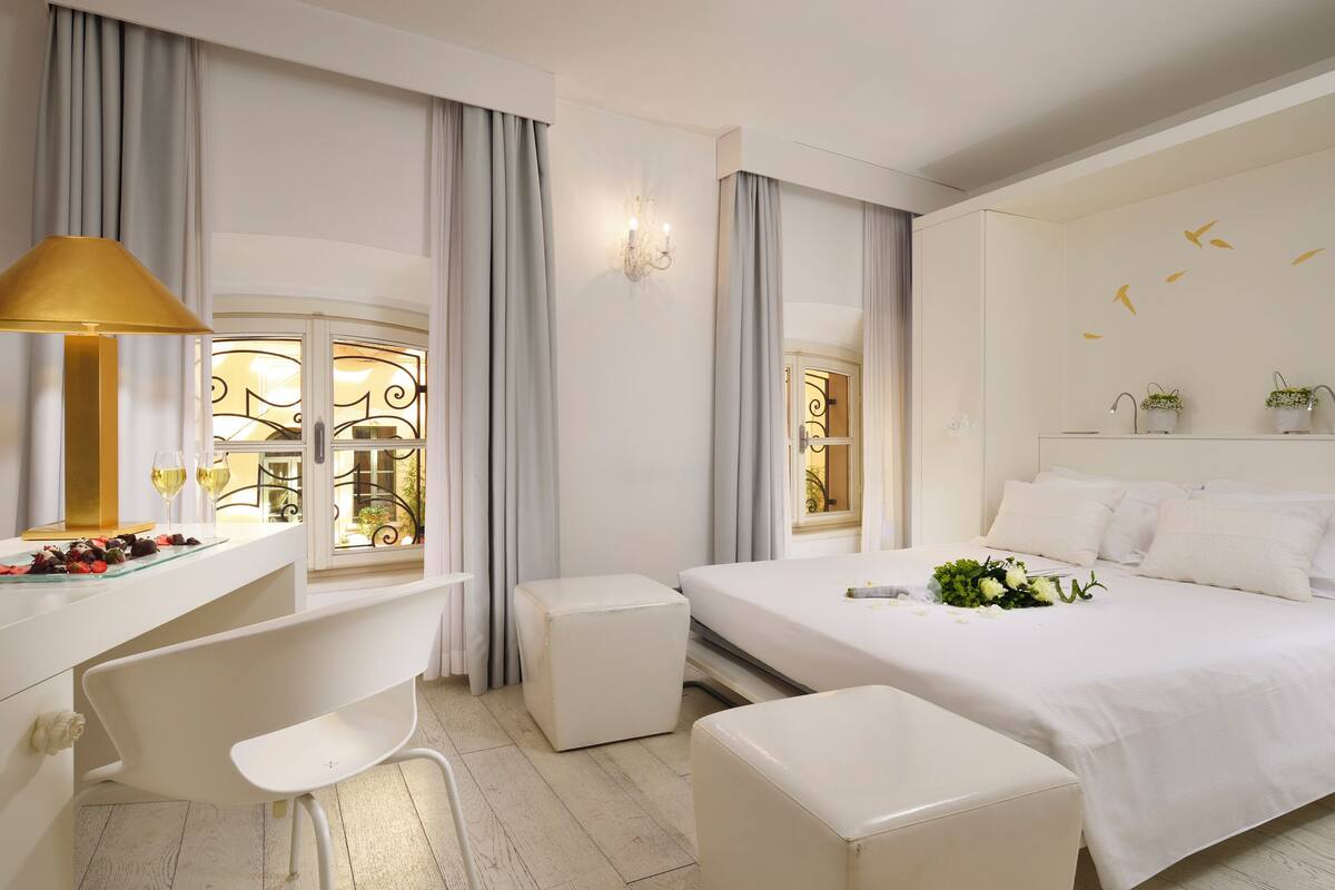 Una habitación de hotel moderna con una cama, un escritorio, una silla y una mesita de noche con una lámpara.