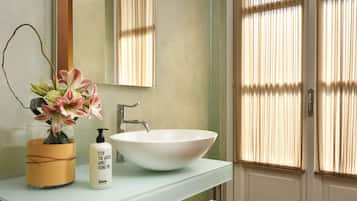 A bathroom with a white sink, a mirror, and a vase with flowers.