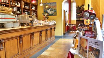 Interior de un restaurante con una barra de madera, estantes con botellas, una máquina de café y un letrero que dice 'La Cantina'.