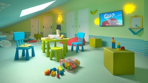 Ein Spielzimmer für Kinder mit schrägem Dach, einem Fernseher und verschiedenen Spielzeugen.
