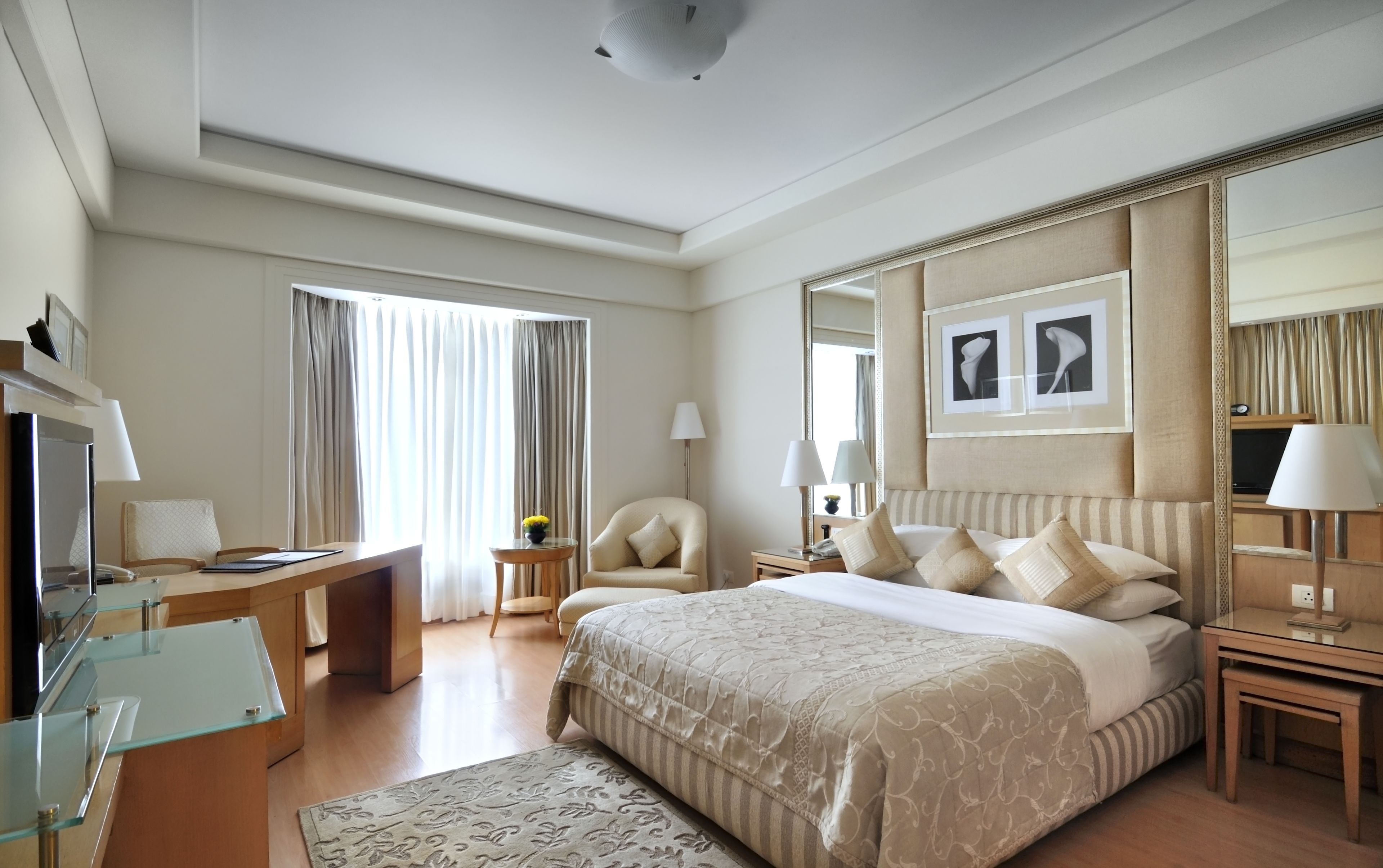 Una habitación de hotel con una cama grande, un escritorio, una silla, un televisor y un espejo.